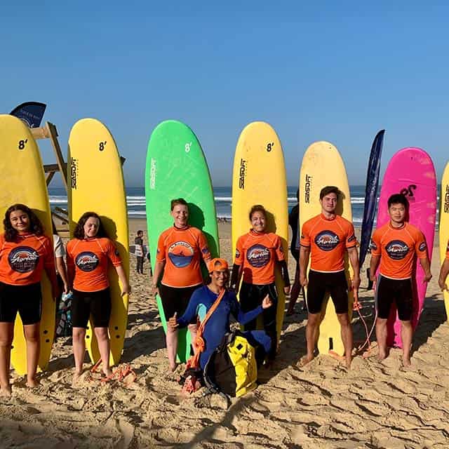 jeunes en ligne sur la plage avec des planches de surf dans leur dos